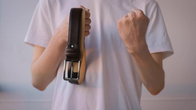 A man with a belt in his hands shakes his fist on an isolated background