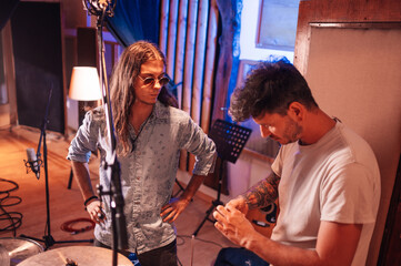 Two male musicians assembling drums in a soundproof booth in a music studio