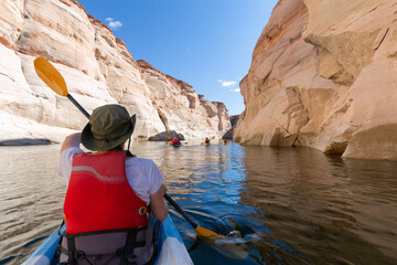 Back of young happy girl kayaking on lake powell with paddle and kayak and life vest on Antelope slot canyon in Arizona during summer © xamnex