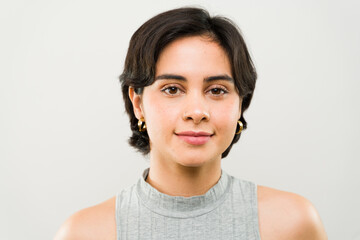 Latin woman with short dark hair and a nose ring is posing in a studio setting, wearing a casual...
