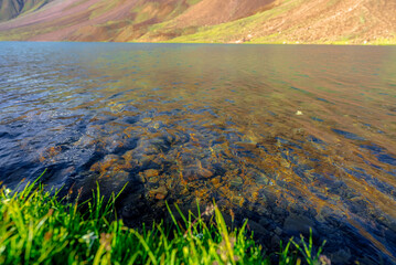 Chandratal lake, Moon Lake during Sunset with crystal clear water in between mountains surrounded by snowcapped mountains.