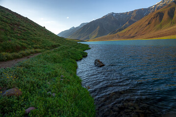 Chandratal lake, Moon Lake during Sunset with crystal clear water in between mountains surrounded by snowcapped mountains.