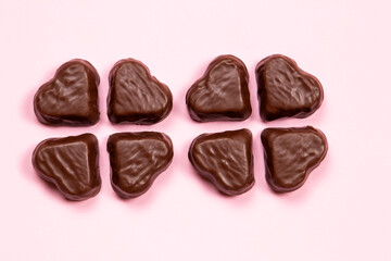 Heart-shaped chocolate candy on a pink background