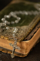Close-up of a rosary draped over an old Bible symbolizing faith and prayer.