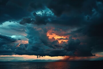 A dramatic sunset skims the horizon as dark storm clouds gather over an open field, creating a stunning contrast of colors in the late evening sky