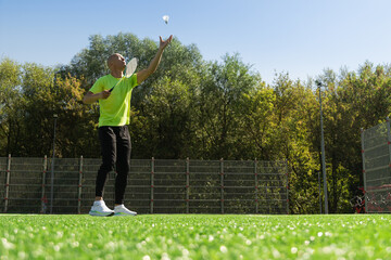 Man playing badminton on green sport court in public park. Outdoors. Summer sports game. Copy space.