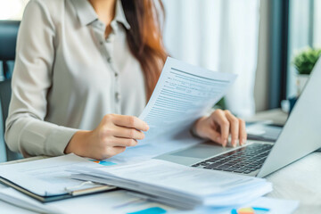 Busy 40 years old business woman working in office checking documents. Mid aged businesswoman accounting manager executive or lawyer using laptop reading paper file financial report, tax invoice