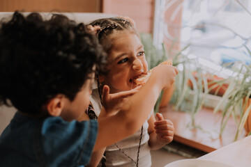 Two small children are eating pizza in a pizzeria