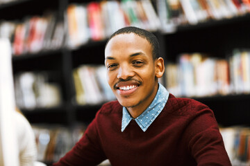 Education, smile and portrait with man in library for scholarship, knowledge or learning. Research, university and exam with person studying on college campus for project, academy or school resource