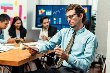 Portrait of businessman or analyst looking at camera with his colleague analyzing data analysis in dynamic business strategy investment planning meeting. Meticulous