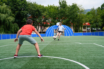 Mother and son playing soccer, as the boy practices blocking kicks on an outdoor field.