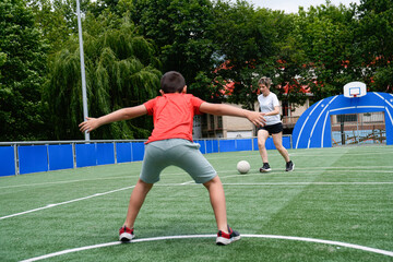 Obraz premium Mother playing soccer with her son, preparing to kick the ball on an outdoor field.