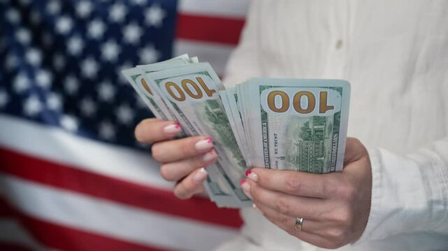 Counting money dollars USD on waving american national flag background. Finance, economic crisis, united states currency, symbol of independence.