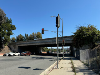 highway overpass over a broad city street, traffic lights and cars and trees - Encino, California