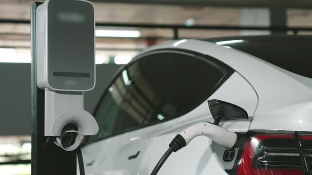 Slow motion EV electric car recharge at shopping center indoor parking lot charging in downtown city showing urban sustainability green clean rechargeable energy lifestyle of electric vehicle innards