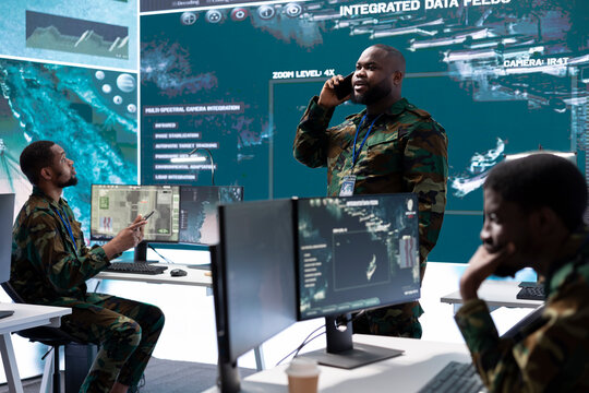 Group of soldiers in a high tech office environment collaborates on intelligence analysis, data processing and strategic planning. Maintaining national security and operational command service.