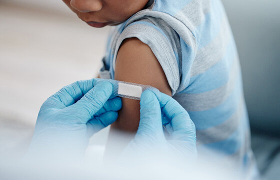 Healthcare, child or plaster on arm with doctor hands, healing or injection site for vaccine. Kid, expert or bandage in clinic with PPE, support or wellness with flu shot for prevention or protection