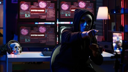 Evil programmer concealing identity using mobile phone to film ransom video in secret base. Scammer with anonymous mask using cellphone to record blackmail footage, threatening victims, camera A