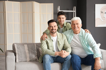 Teenage boy with his dad and grandfather sitting on sofa at home