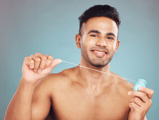 Studio, portrait and man with dental floss for wellness, gum hygiene and health with cleaning for fresh breath. Male model, teeth and string by blue background for mouth, gingivitis and oral care