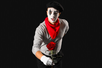 Male pantomimist with flower on black background