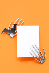 Blank card and Halloween decorations on orange background, top view