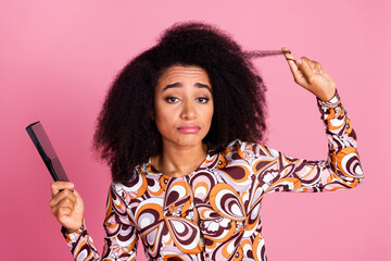 Photo of pretty unhappy lady dressed print shirt combing hair curl empty space isolated pink color...