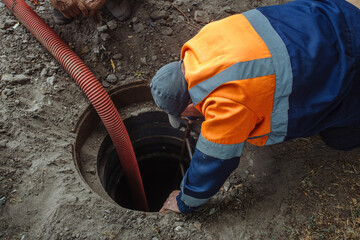 Sewer worker cleaning manhole and unblocking sewers the street sidewalk