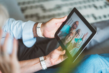 Senior couple hands holding digital tablet, while on video call with family