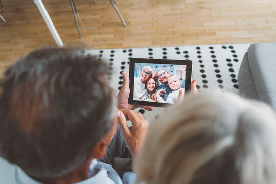 Over the head view of senior couple holding digital tablet, on video call with family - Powered by Adobe
