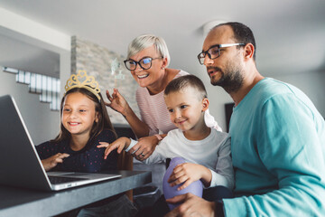 Happy family of four talking to grandparents over video call on laptop