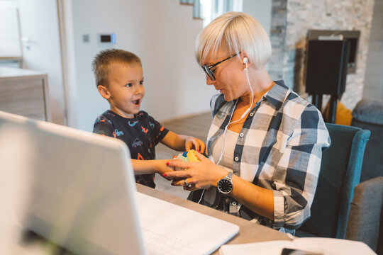 Young boy wanting to cuddle with his mother while she works from home