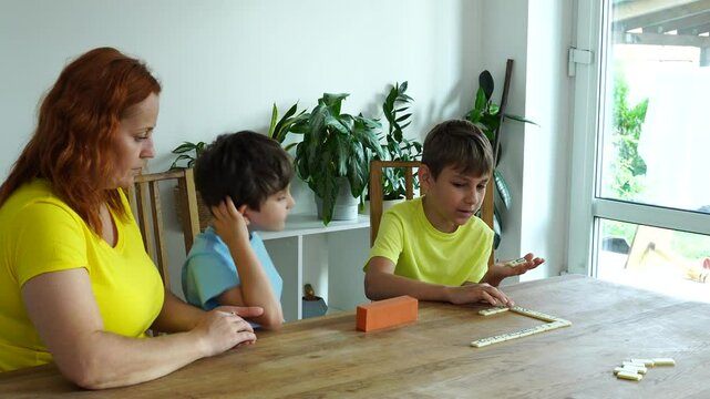 Mother shows kids how to play domino, board game and time together