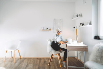 Blonde woman sitting by the desk, working from home