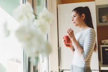 Woman enjoying her smoothie, looking out the window