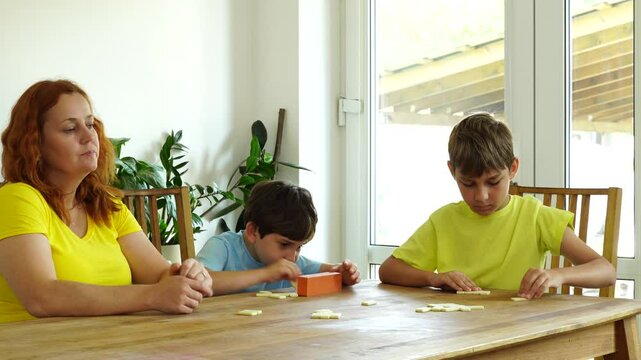 Mother shows kids how to play domino, board game and time together