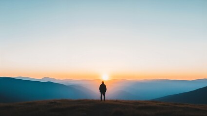 A solitary figure stands before a breathtaking sunrise, basking in the warm hues of orange and gold, surrounded by majestic mountains and tranquil nature as day breaks anew.