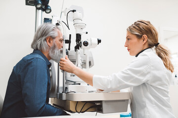 Senior man with beard doing eye test with optometrist