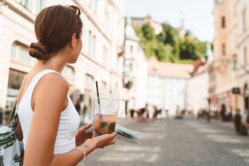Young woman on a walk in the city center of Ljubljana with ice tea in her hands