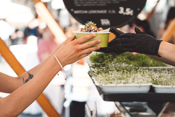 Obraz premium Chef at a local food market handing poke bowl to costumer