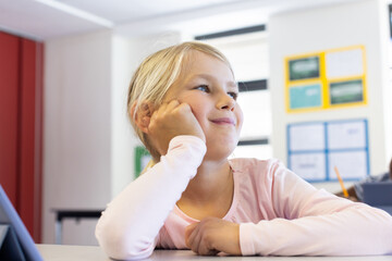 In school, girl daydreaming at desk, looking away with thoughtful expression