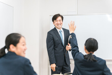 塾・学校の教室で中学生・高校生に勉強を教える男性講師・教師
