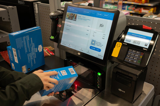 Tigard, OR, USA - Dec 5, 2023: A shopper scans a product barcode on packaging at the self-checkout lane in a Walmart Supercenter in Tigard, Oregon.