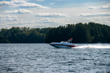 pleasure boat on northern lake with forest along the shore