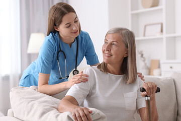 Obraz premium Smiling healthcare worker supporting senior patient indoors