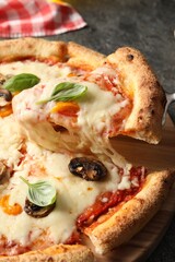 Taking piece of delicious vegetarian pizza at table, closeup