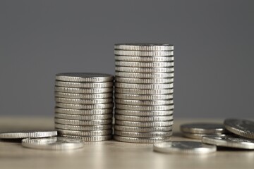 Stacked coins on wooden table against grey background, closeup. Salary concept