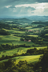 Obraz premium Aerial view of lush green rolling hills and farmland under a cloudy sky