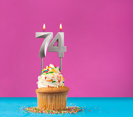 Cupcake with birthday candle number 74 - Anniversary card on blue and violet background