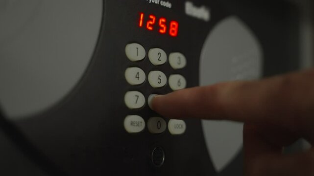 Close up on hand punching keypad and opening security safe box or vault in hotel. Person opening the small safe after clicking the correct code or lock combination and the metal door opens up